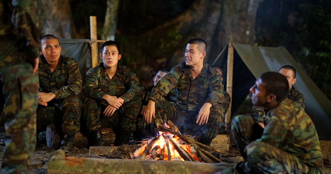 A group of soldiers in camouflage uniforms sit around a campfire in a dark forest setting, from the film "2359 The Haunting Hour".