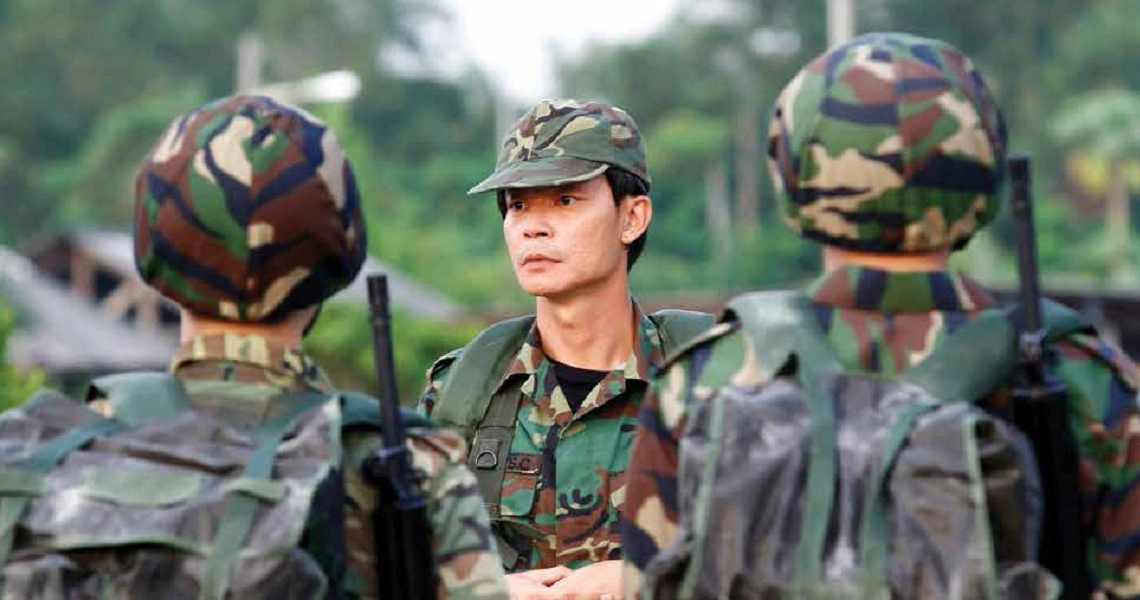 A tense scene from the film "2359" shows soldiers in camouflage uniforms, with one soldier in focus looking alert in a jungle setting.