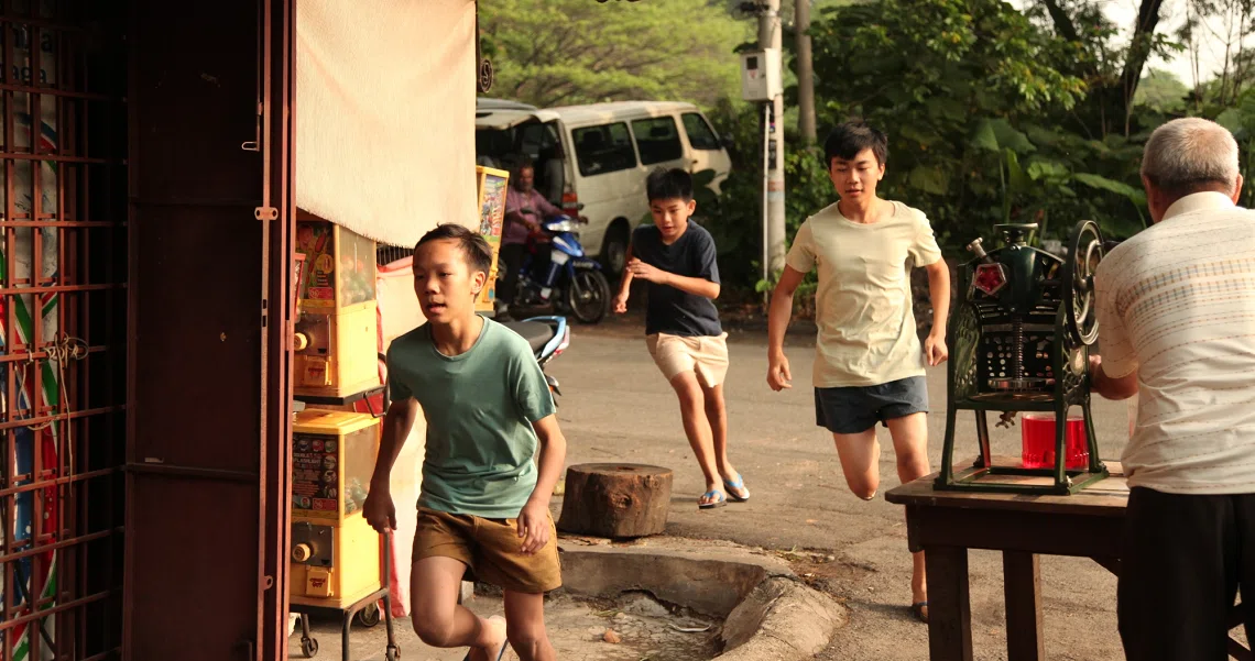 A scene from the film "7 Letters" showing people walking on a street, with a child in the foreground and adults behind.