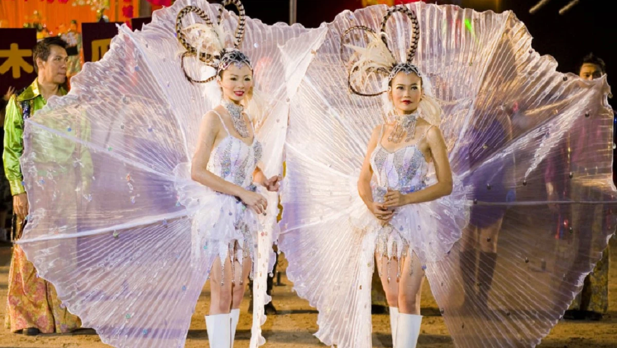 Two performers in elaborate white costumes with large fan-like wings perform in a scene from the Singaporean film 881.