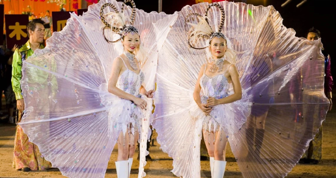 Two performers in elaborate white costumes with large fan-like wings perform in a scene from the Singaporean film 881.