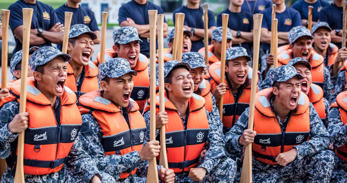 Ah Boys To Men 3 Frogmen film still shows excited naval recruits in life jackets and camouflage uniforms holding oars.