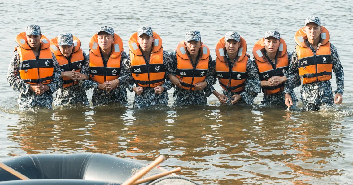 Ah Boys To Men 3 Frogmen film still shows a line of soldiers in orange life vests wading through water during training.