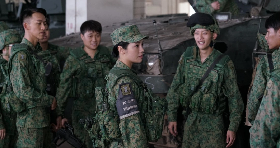 Soldiers in camouflage uniforms gather in a military setting, a scene from the film "Ah Boys To Men 4".