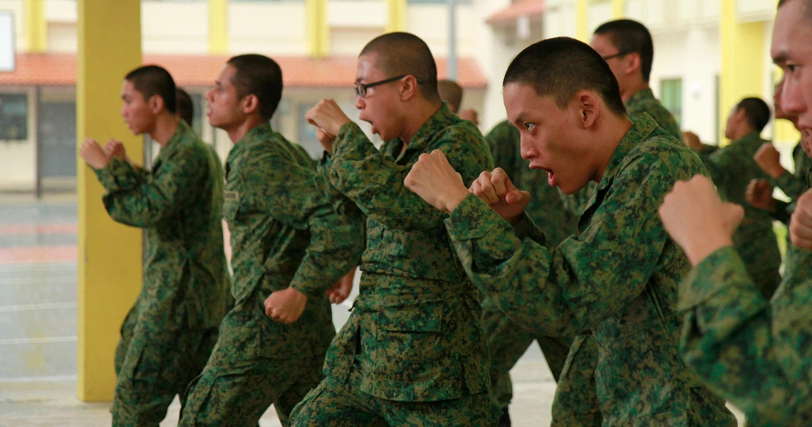 A group of soldiers in green uniforms stand in formation during a scene from the Singaporean film "Ah Boys to Men".