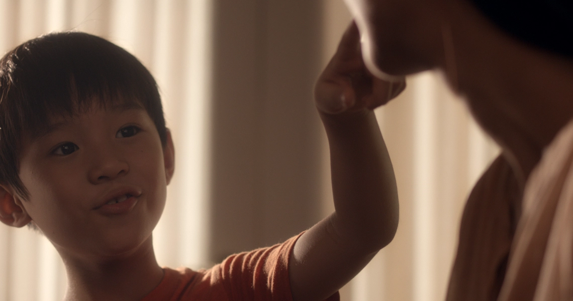 A young boy reaches out to an adult in a poignant scene from the Singaporean film "Bring Back The Dead".