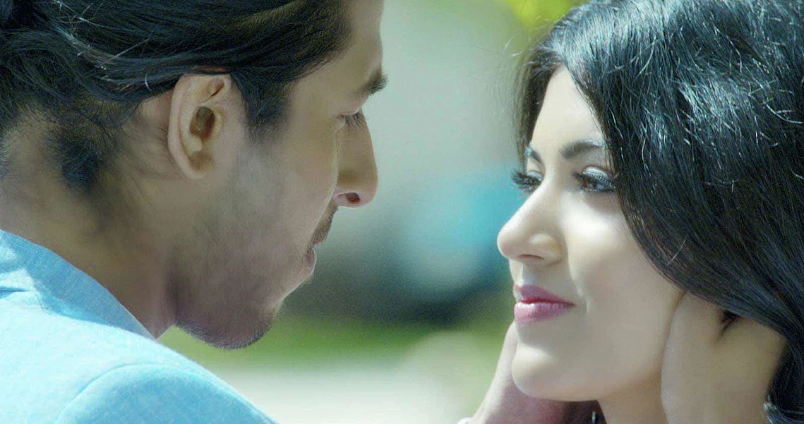 A romantic scene from the film Chennai2Singapore showing a close-up of a couple gazing at each other affectionately outdoors.