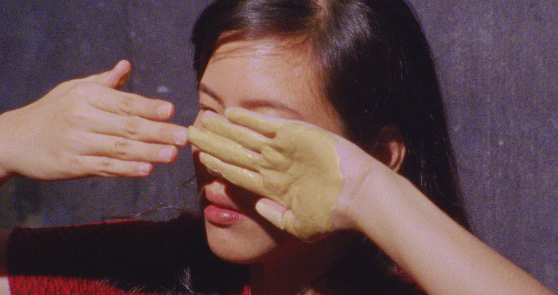 A scene from the film "Demons" showing hands covering a person's eyes, creating a mysterious atmosphere.