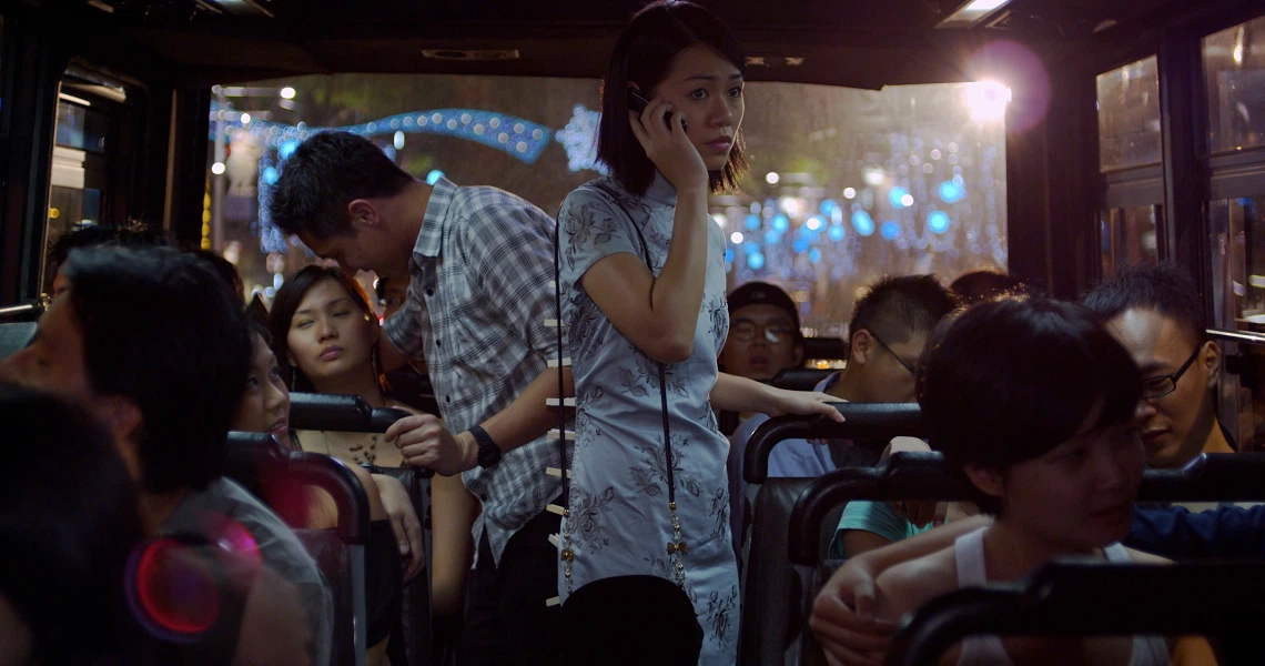 A crowded bus scene from the film "Forever", showing a woman on her phone amidst passengers, with city lights visible through the windows.