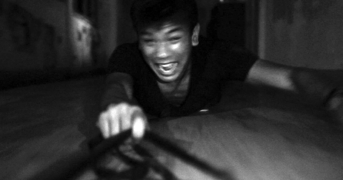 A terrified young man crawls on the floor in a dark, eerie setting from the Singaporean horror film "Haunted Changi".