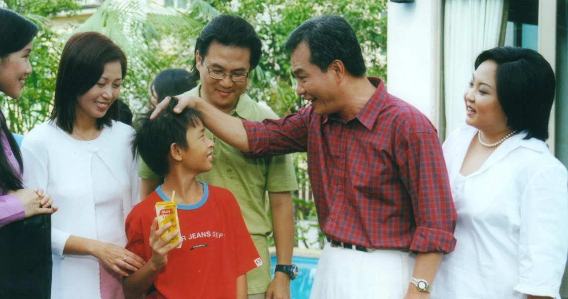 A family scene from the film "I Not Stupid" showing adults and children interacting outdoors, highlighting family dynamics.