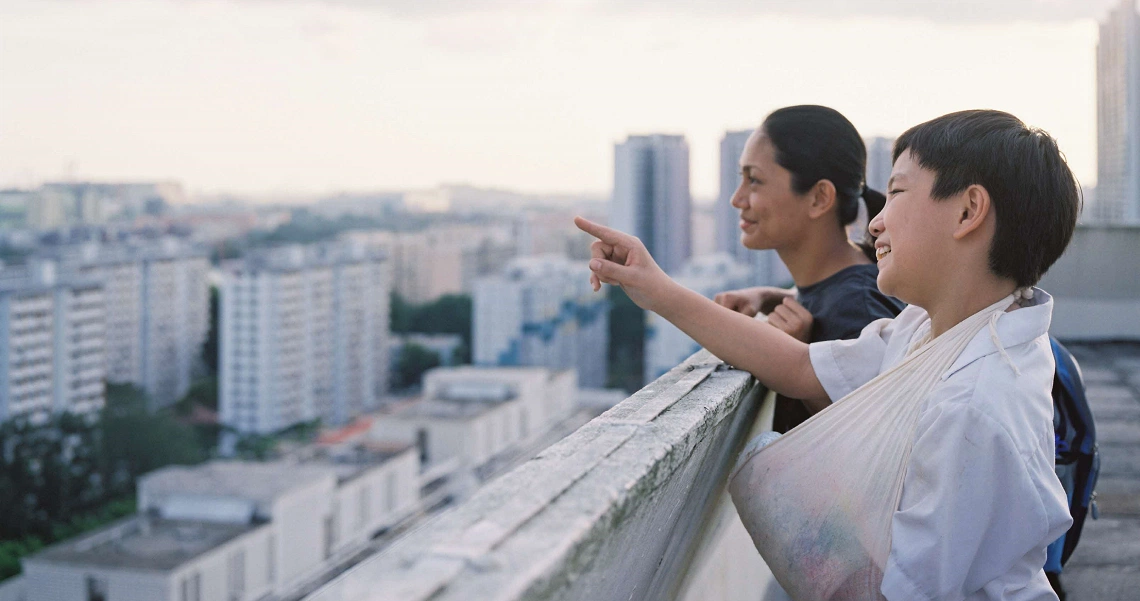 A scene from the film Ilo Ilo showing two characters overlooking a cityscape, pointing at something in the distance.