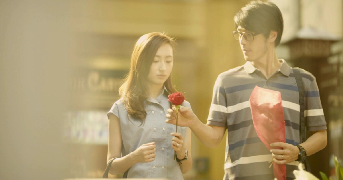 A scene from the film Judgement Day showing a young couple exchanging gifts, with the man offering a red flower.