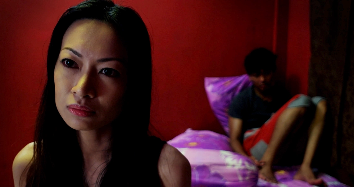 A dramatic scene from the film Konpaku shows a woman with long dark hair in the foreground, with a figure on a bed in the background.