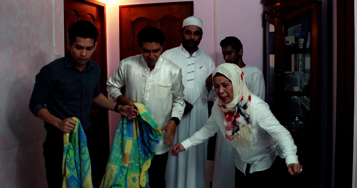 A group of people in traditional and modern attire gather in a dimly lit interior, showcasing a scene from the film Konpaku.