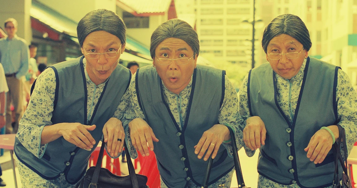 Film still from Liang Po Po showing three identical elderly women in matching outfits with surprised expressions in a public setting.