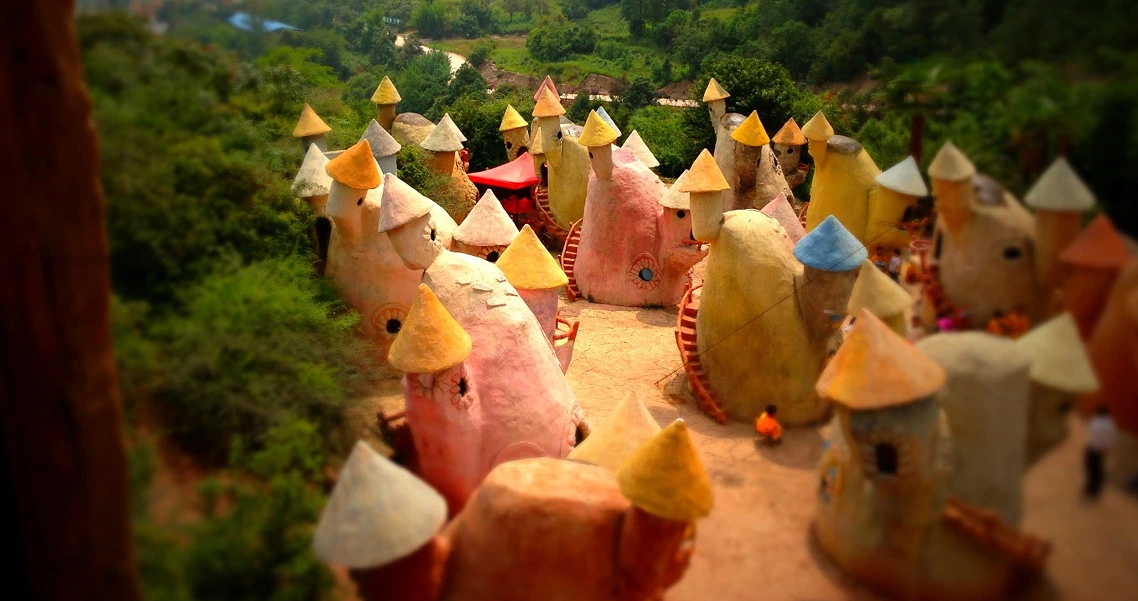 Colorful miniature houses in a forest setting from the film "Little People Big Dreams", showcasing whimsical architecture.