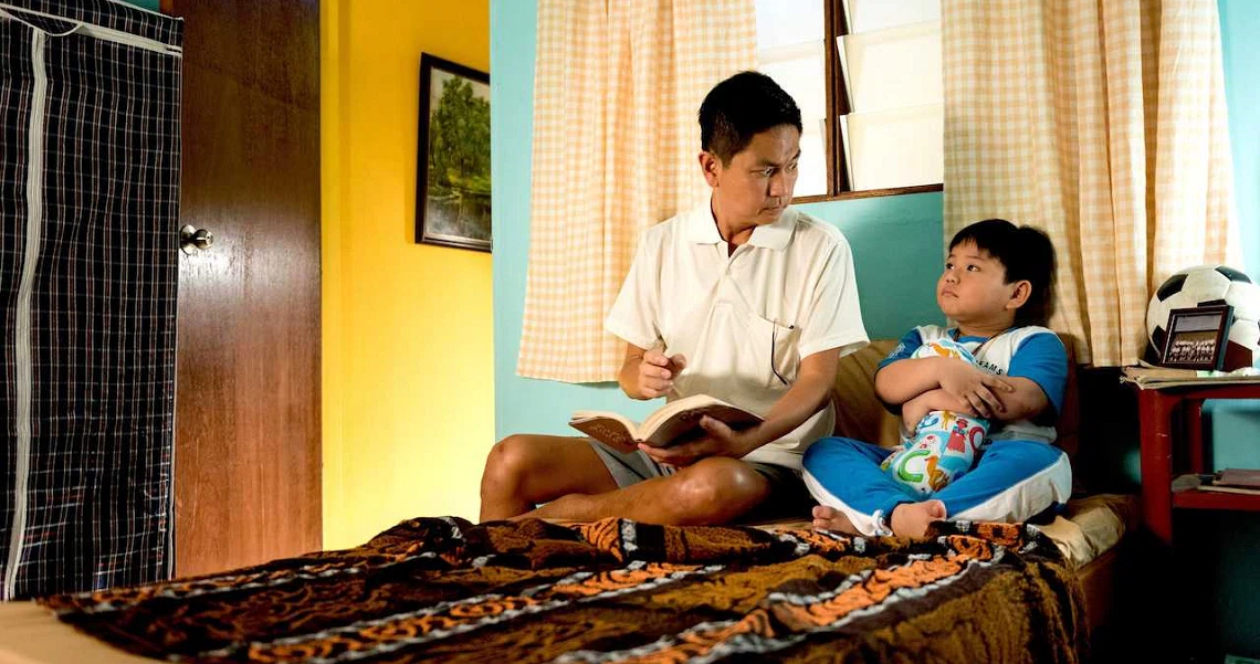 A scene from the film Lucky Boy shows two boys sitting on a bed, engaged in conversation in a colorful bedroom setting.