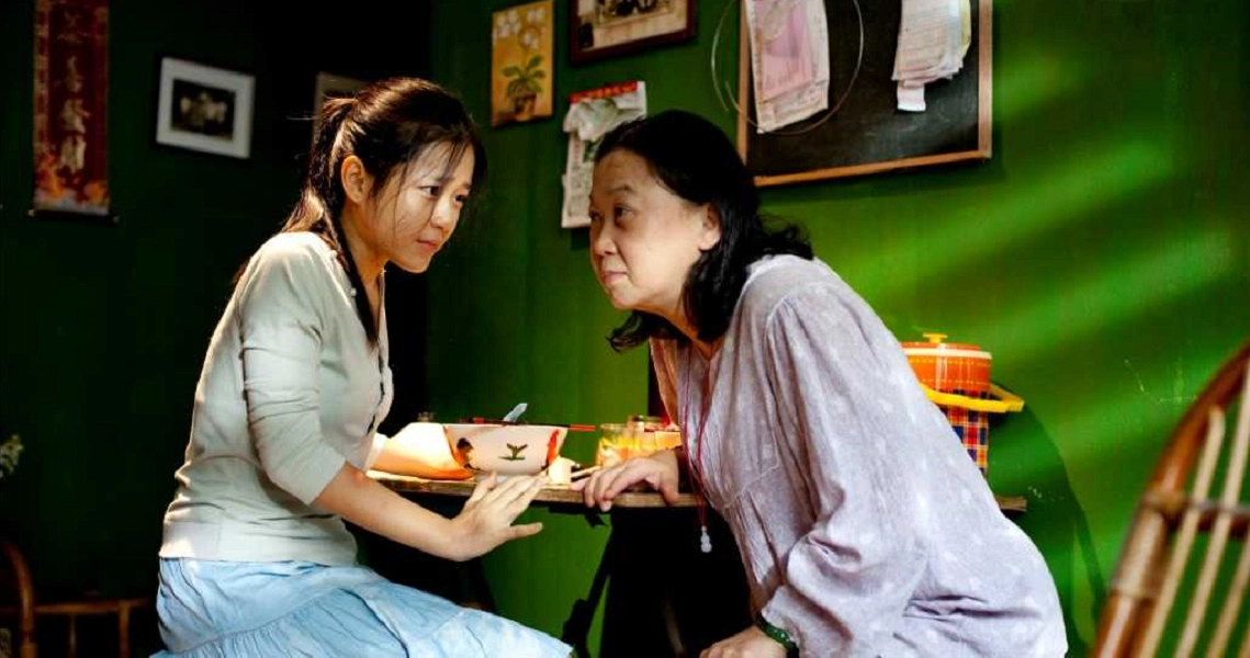 A scene from the Singaporean film 'Perfect Rivals' showing two characters engaged in an intense conversation.