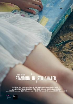 Film poster for "Standing in Still Water" featuring a close-up of a person's legs in white clothing near water, with film credits overlaid.