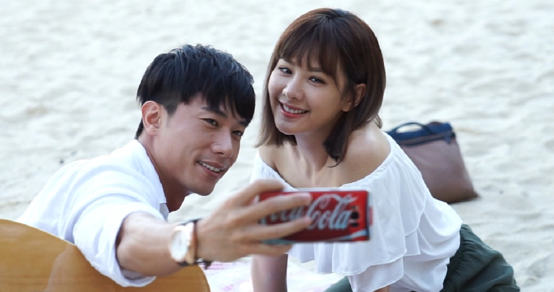 A couple takes a selfie on the beach in a scene from the film 'The Big Day', capturing a romantic moment.