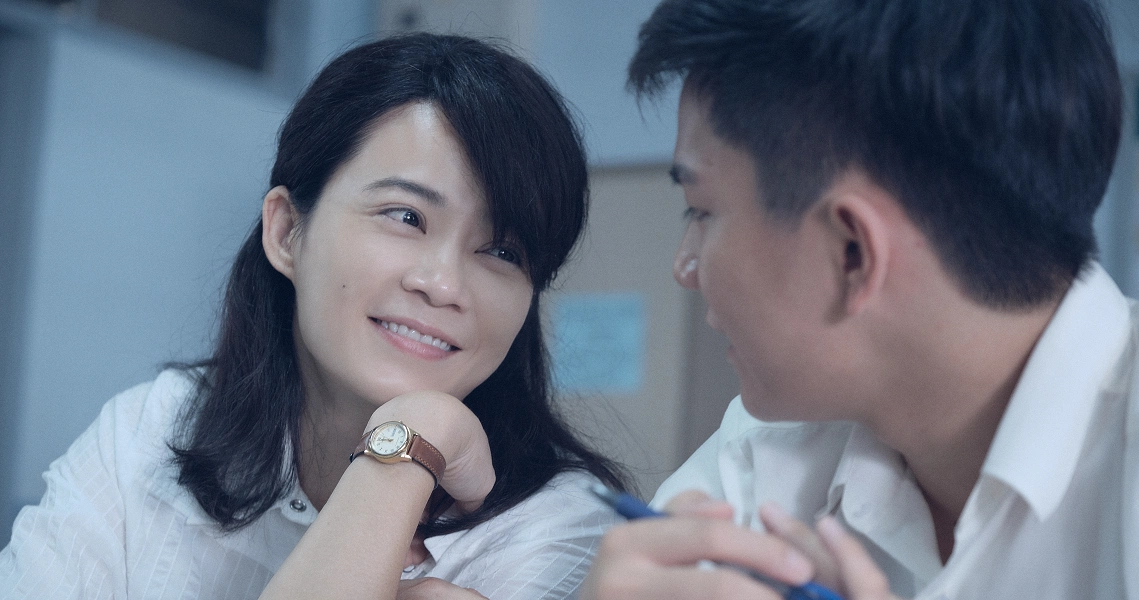 A woman smiles warmly at a young boy in a scene from the film "Wet Season", depicting a tender moment between characters.