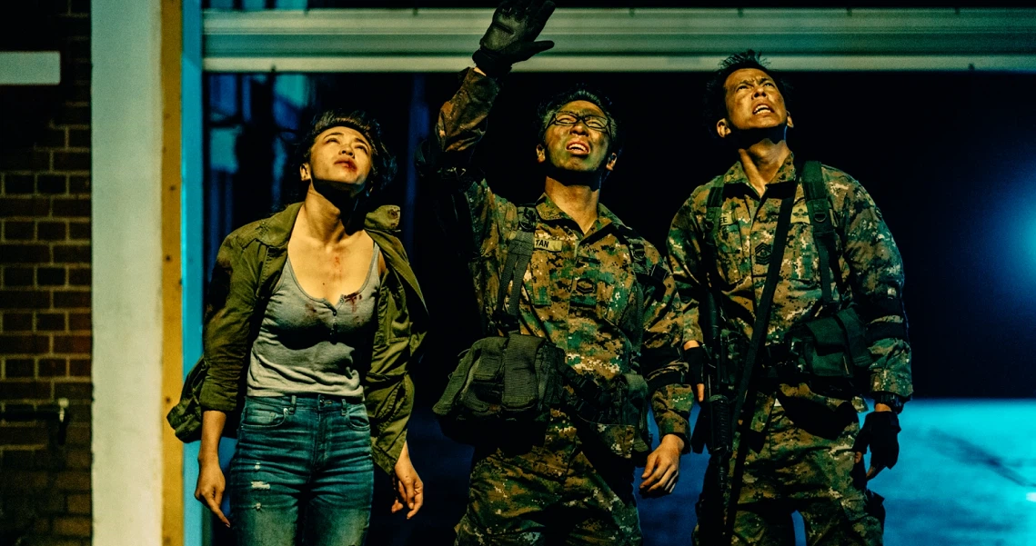 Three characters from the film Zombiepura stand alert, with two soldiers in camouflage and a woman in civilian clothes looking upward.