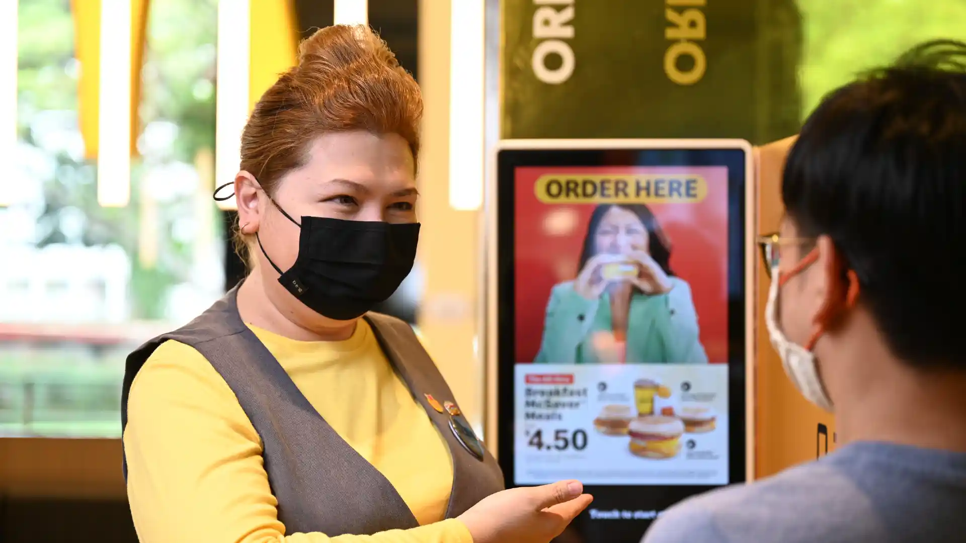 A McDonald's staff speaking with a customer, representing the success of data-driven analytics in F&B through the BDDB programme