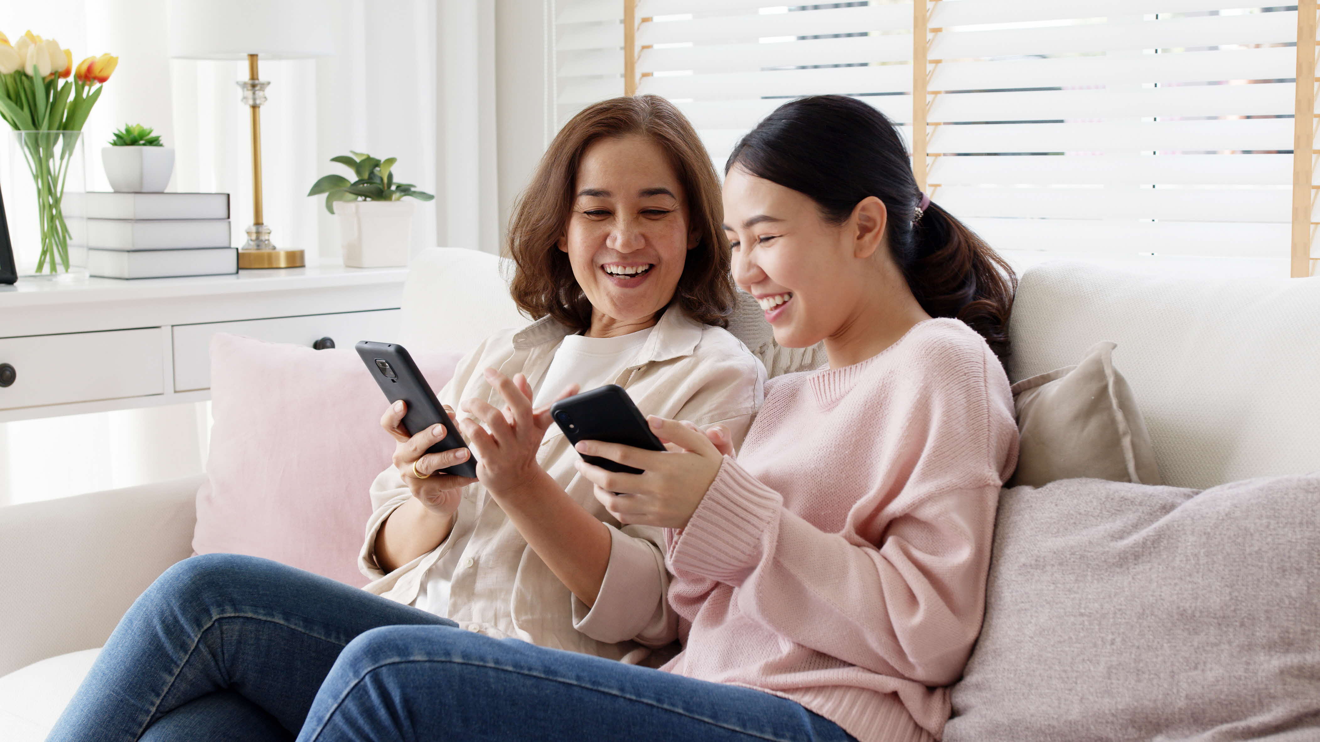 Mother and daughter on the couch using social media apps on their phones